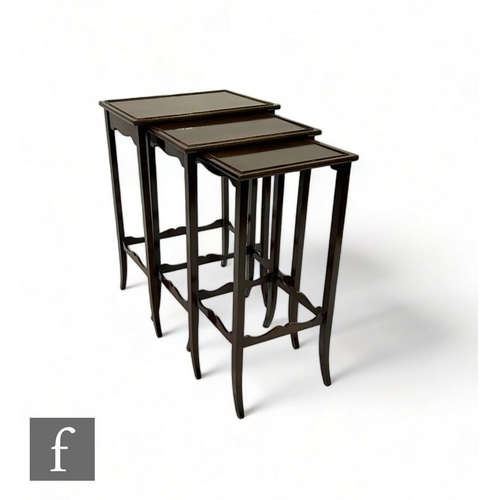 532 - An Edwardian mahogany nest of three occasional tables, on slender splayed legs united by shaped rail... 