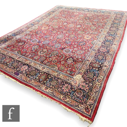 459 - A Heriz style carpet, all over floral and fruit design on a red ground within a multi running floral... 