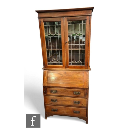 513 - An Edwardian crossbanded mahogany bureau bookcase enclosed by a pair of coloured leaded light doors ... 