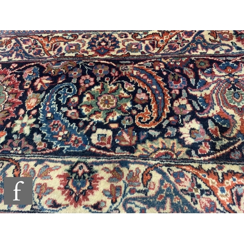 459 - A Heriz style carpet, all over floral and fruit design on a red ground within a multi running floral... 