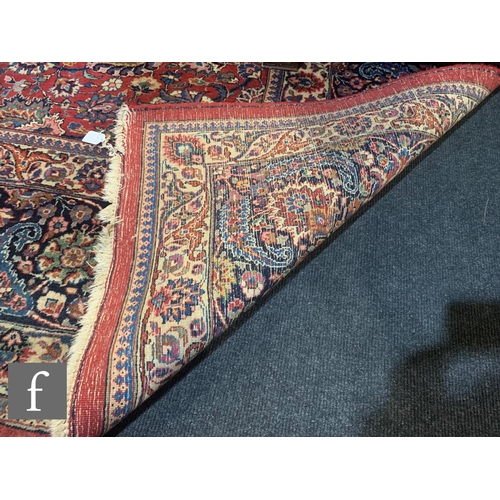 459 - A Heriz style carpet, all over floral and fruit design on a red ground within a multi running floral... 