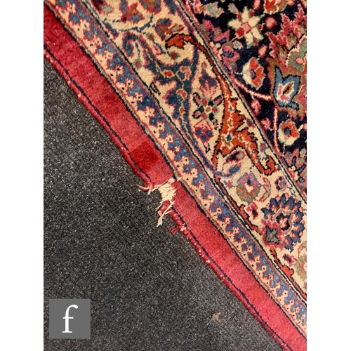 459 - A Heriz style carpet, all over floral and fruit design on a red ground within a multi running floral... 