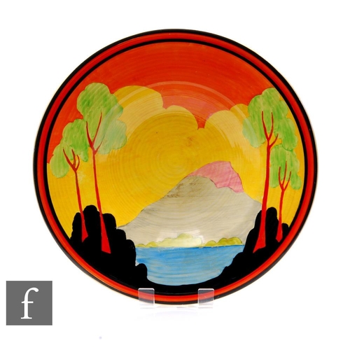 Clarice Cliff - Applique Etna - An 18 inch ribbed charger circa 1930, hand painted with a stylised landscape with trees to the foreground and a mountain below a deep orange sky with black and orange banding, partial Bizarre mark to the reverse.