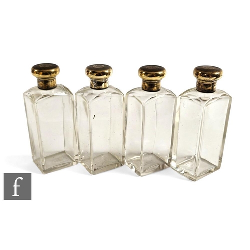 257 - A set of four cologne bottles, plain rectangular cut shouldered bottles each terminating in a silver... 