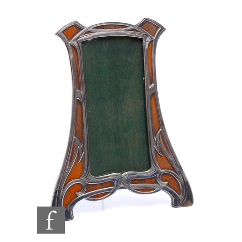 274 - An Art Nouveau white metal shaped rectangular easel photograph frame with whiplash decoration overla... 