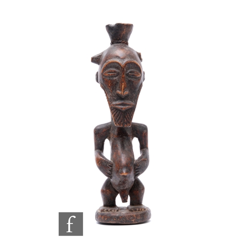 790 - A late 19th to early 20th Century bearded male African fertility figure, standing with hands holding... 