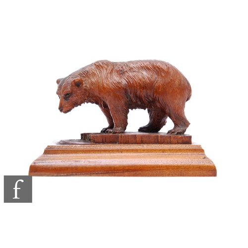 796 - A late 19th to early 20th Century Black Forest carving of a bear fishing for salmon, standing on a p... 