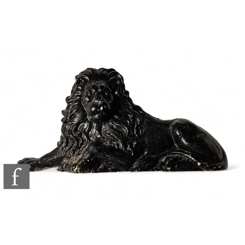 834 - A mid 19th Century black painted cast iron recumbent lion with thick mane and outstretched paw, leng... 