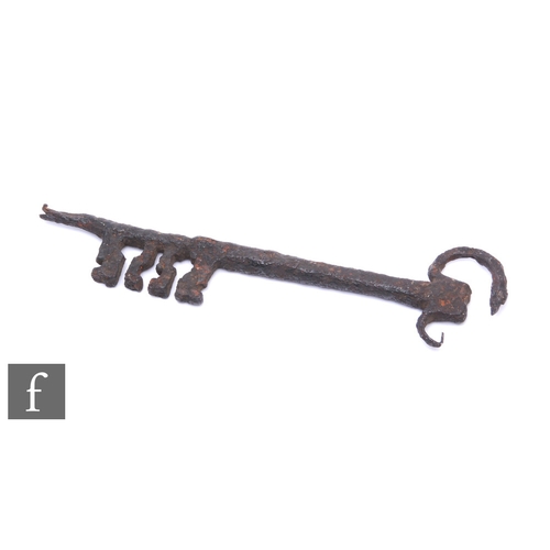 838 - A large post Medieval iron key with four shaped teeth, length 30cm, damaged.