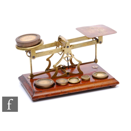 252 - A set of Edwardian brass postal scales with associated weights, on mahogany plinth base, width 28cm.