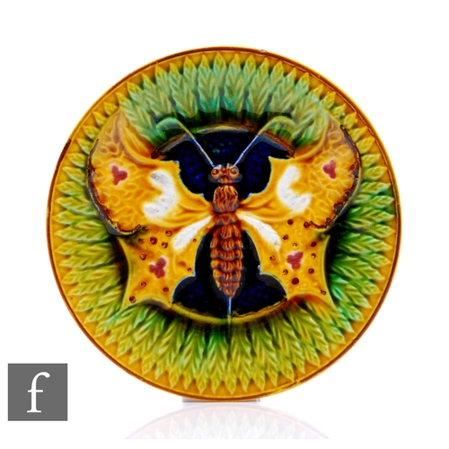 69 - An early 20th Century English Majolica plate, decorated with a winged moth on a blue green and yello... 