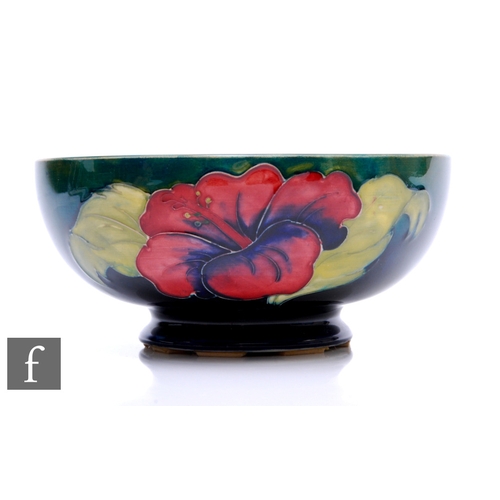 130 - A post war Walter Moorcroft pottery bowl of footed circular form, decorated in the Hibiscus pattern ... 