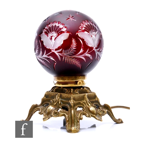 451 - A small glass table lamp, of globular form, cased in deep ruby over clear and cut to reveal stylised... 