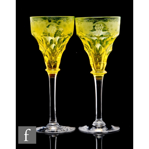 454 - A pair of early 20th Century John Walsh Walsh wine glasses in deep citron with engraved fruiting vin... 