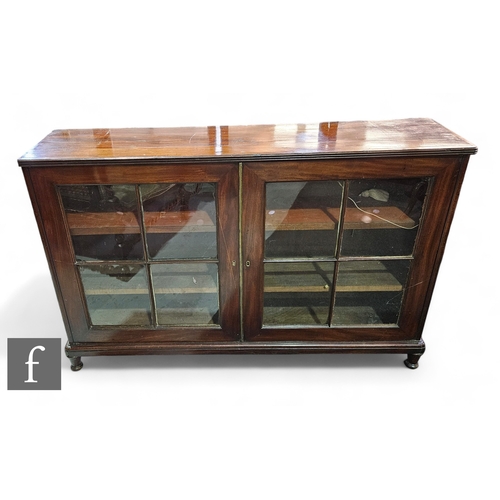 1044 - An Edwardian mahogany bookcase of narrow proportions enclosed by a pair of bar glazed doors below a ... 