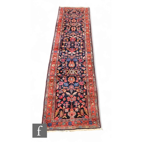 1073 - A Hamadan runner, all over floral design on a deep blue ground within multi flower head border, 296c... 