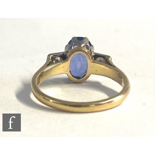 72 - An 18ct hallmarked sapphire and diamond three stone ring, central oval cornflower blue sapphire flan... 