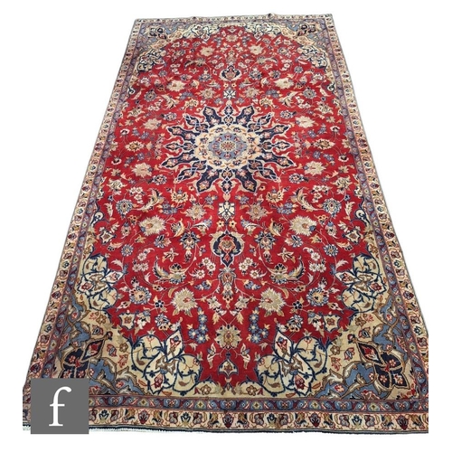 388 - A Persian Isfahan rug, the red central ground with blue and ivory coloured floral ground,  354cm x 2... 