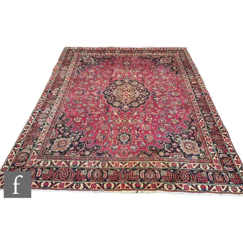 391 - A large Persian Isfahan wool carpet, the red ground with black and blue floral motifs set within geo... 