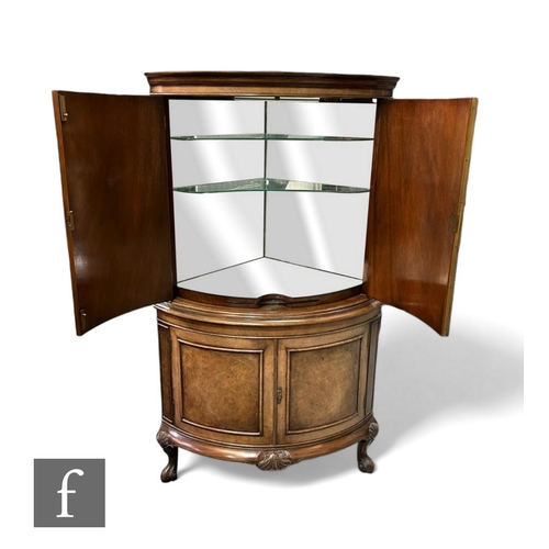 392 - A Queen Anne style walnut floorstanding cocktail cabinet, the mirrored interior enclosed by shaped b... 