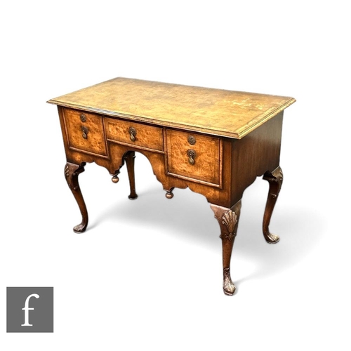 394 - A George I style walnut lowboy, the quartered and crossbanded top over three drawers and an arch, br... 