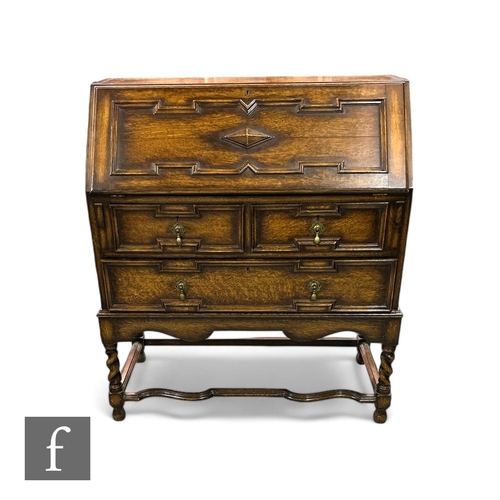 400 - A 1920s oak bureau, the fitted interior enclosed by a geometric moulded front fall over three long d... 