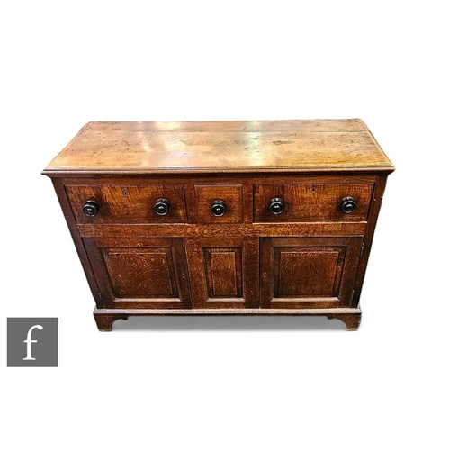 409 - A George III oak dresser fitted with three drawers above a cupboard base, turned ebonised handles be... 