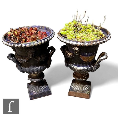 422 - A small pair of cast iron campagna shaped terrace urns on square bases, height 34cm. (2)