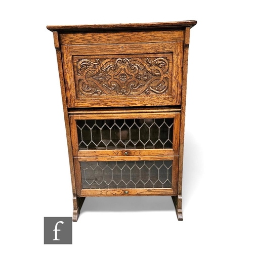 427 - A 1920s carved oak combination bookcase, the interior enclosed by a carved panel over two sectional ... 