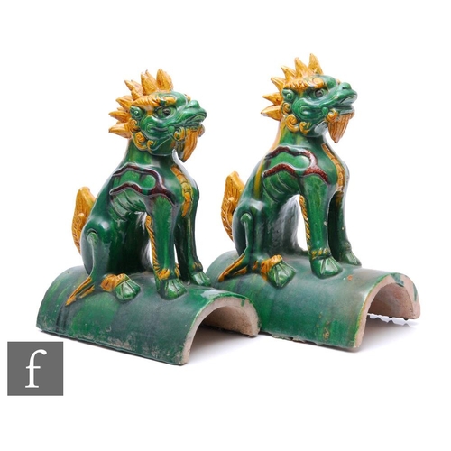 77 - A pair of Ming Sancai styl roof tiles, the arched tile surmounted by a seated shishi lion, in green ... 