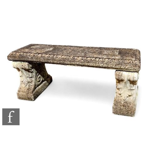 394A - A reconstituted stone garden bench, raised in two scalloped pedestal plinth, with flat top, height 4... 