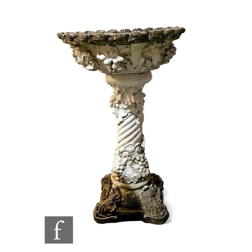 422A - A reconstituted stone garden bird bath of pedestal form, decorated with vines and grapes, on a rocai... 