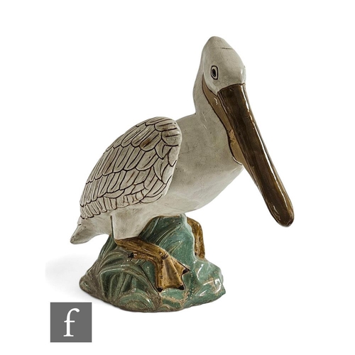 555 - A decorative terracotta figure of a pelican, the white glazed bird, perched on a rocky outcrop, unsi... 