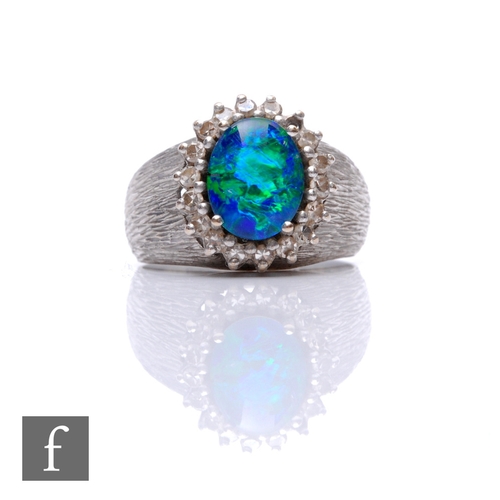 63 - An 18ct hallmarked white gold opal doublet and diamond cluster ring, central opal within a border of... 