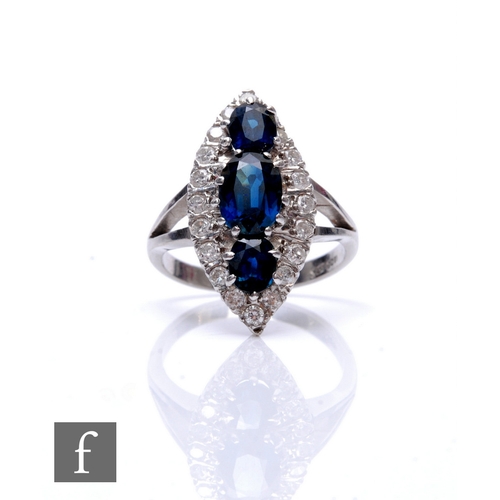 65 - An 18ct white gold marquise shaped sapphire and diamond cluster ring, three vertically set sapphires... 