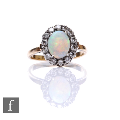 74 - An early 20th Century 18ct opal and diamond cluster ring, central oval opal, length 9mm, within a bo... 