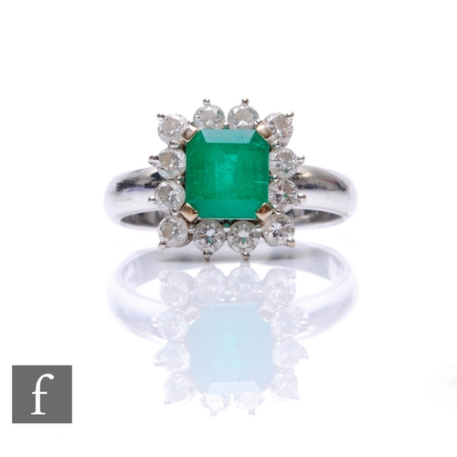 76 - An 18ct white gold emerald and diamond cluster ring, square cut emerald, width 7mm, within a border ... 