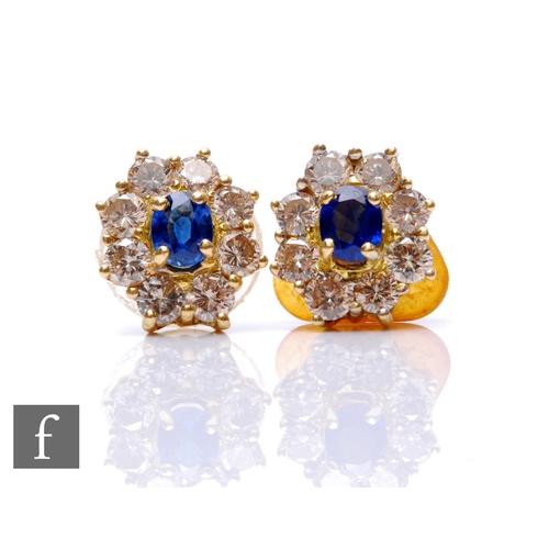 80 - A pair of 18ct hallmarked sapphire and diamond stud earrings each with a central oval sapphire, leng... 