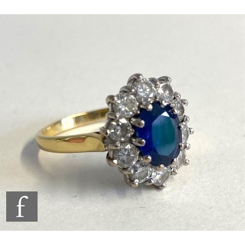 75 - An 18ct hallmarked sapphire and diamond cluster ring, central oval sapphire, length 9mm, within a bo... 