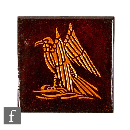 314 - A 6 inch plastic cement tile with tube lined decoration of a stylised eagle in orange against the tr... 