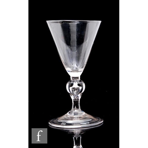 124 - An 18th Century drinking glass circa 1750, the large pointed round funnel bowl above a hollow blown ... 