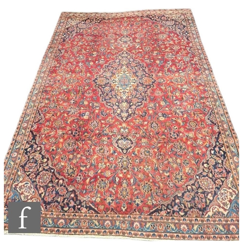 722 - A large Persian Corcoran wool carpet, with central floral shaped lozenge surrounded by blue ochre an... 