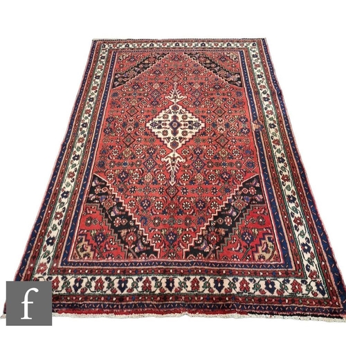 723 - A Persian Hamadan rug, the red ground with central diamond shaped lozenge and scalloped black border... 