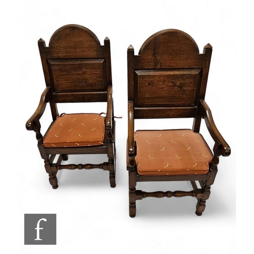 782 - A pair of 20th Century oak elbow chairs, the arched backs over planks seats, down swept arms, on tur... 