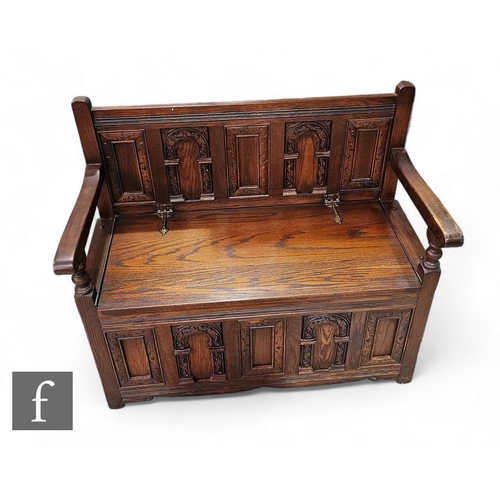 778 - A 17th Century style carved oak small settle, the arched panel back over swept arms and conforming b... 