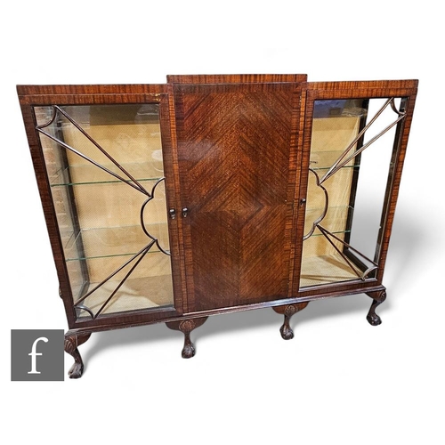 813 - A 1930s mahogany display cabinet, the central cupboard enclosed by a pair of sunburst doors, on cabr... 