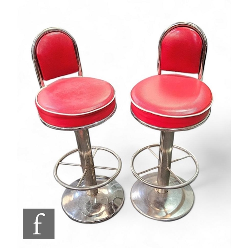 881 - A pair of swivel diner chairs/bar stools, the red leatherette chairs raised on chrome pedestal base.... 