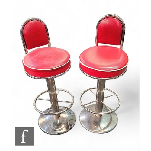 882 - A pair of swivel diner chairs/bar stools, the red leatherette chairs raised on chrome pedestal base.... 