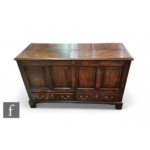 886 - An 18th Century oak mule chest, the part hinged moulded edge top over a quadruple panelled front and... 