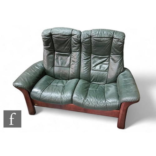 891 - A 1980s mahogany framed two seater reclining sofa upholstered in green leather, on splayed legs, wid... 